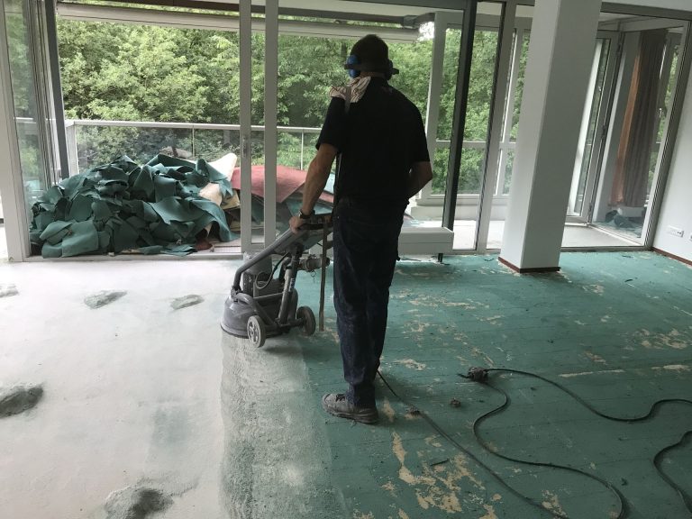 Vakman schuurt een vloer in een lichte ruimte